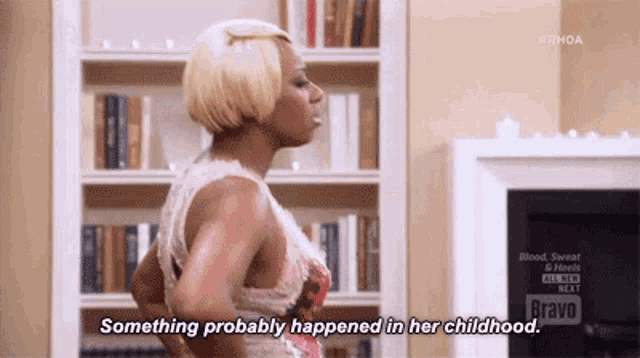 a woman is standing in front of a bookshelf in a living room and saying `` something probably happened in her childhood ''
