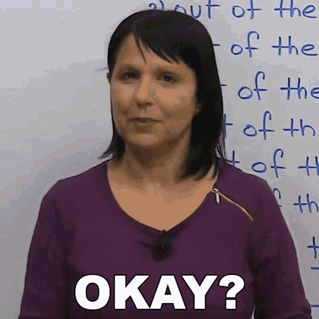 a woman is standing in front of a white board and says okay