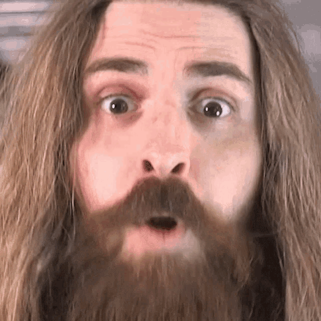 a man with long hair and a beard is making a funny face