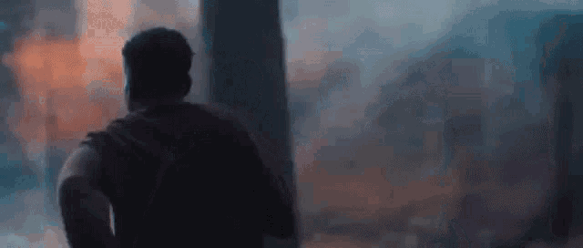 a man in a cape is running in front of a fire in a dark room .