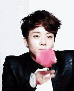 a young man in a suit and tie is holding a pink flower in his hand .