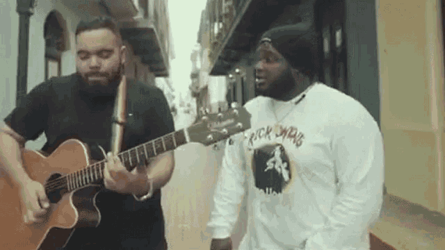 a man wearing a rick owens shirt is playing a guitar