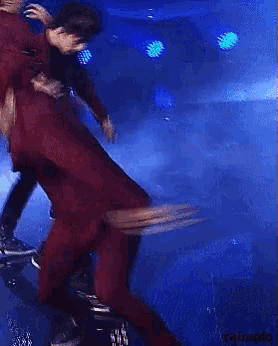 a man in a red suit is dancing on stage