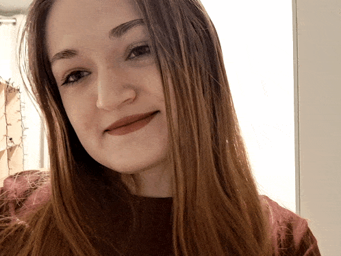 a woman with long brown hair looks at the camera and smiles