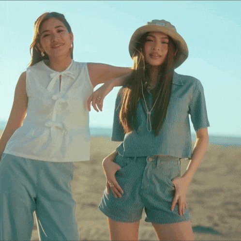 two women standing next to each other on a beach one wearing a hat that says salomon on it