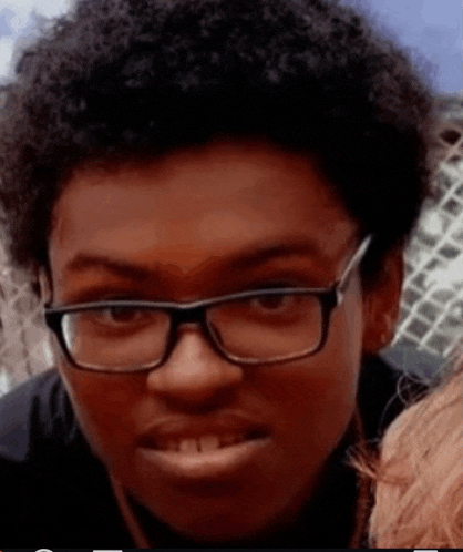 a young man wearing glasses is looking at the camera