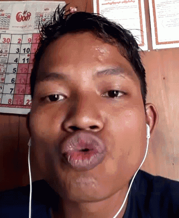 a man wearing ear buds is making a funny face in front of a calendar that shows the date as 30