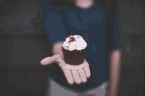 a woman is holding a piece of red velvet cake with white frosting .