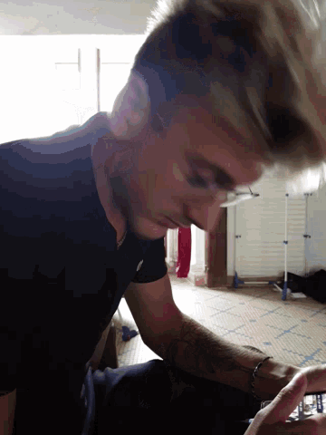 a man with glasses and a tattoo on his arm is looking down