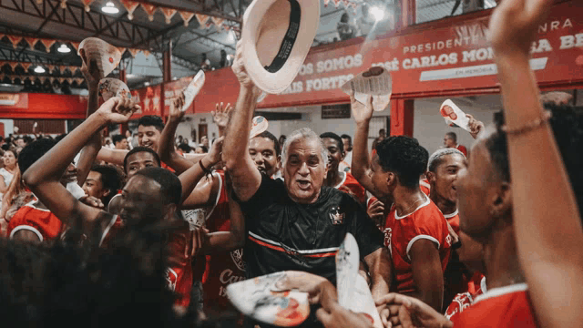 a man holds up a hat in front of a banner that says presidente