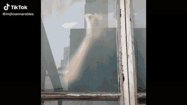 a person 's hand is visible through a window with tiktok written on the bottom right