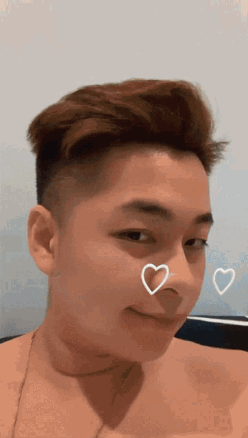 a shirtless man with hearts drawn on his nose