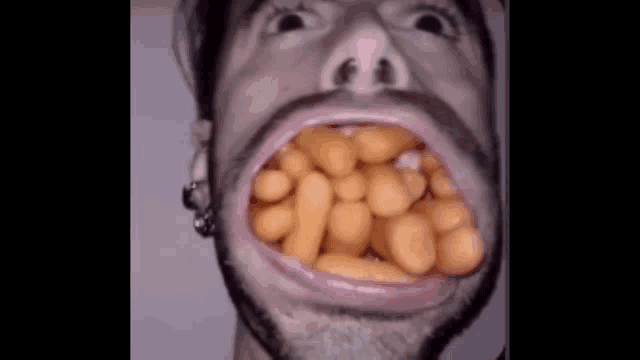 a man with a beard is eating beans in his mouth .