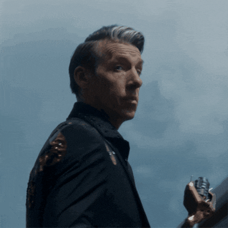 a man in a suit is holding a gun in his right hand