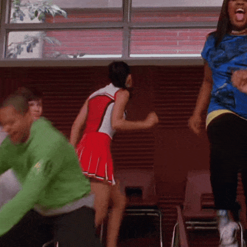 a cheerleader in a red and white outfit is dancing with a man in a green shirt