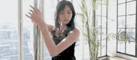 a woman in a black dress is standing in front of a large window