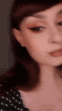 a close up of a woman 's face wearing a polka dot shirt