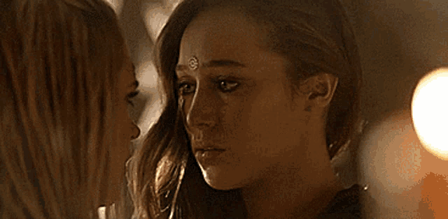 a close up of two women looking at each other with tears coming down their faces .