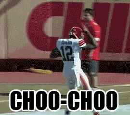 a football player with the number 12 on his jersey is being tackled by another player