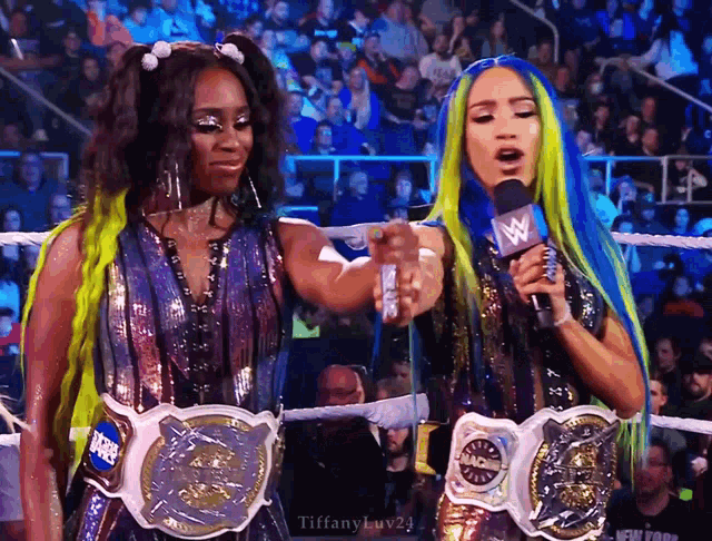 two women in a wrestling ring holding microphones with tiffanyluv24 written on the bottom