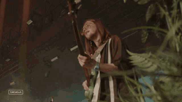 a woman is playing a guitar in front of a sign that says gazelle