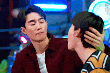 two men are sitting next to each other and one of them is touching the other 's face .