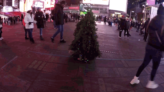 a christmas tree is in the middle of a crowded street in front of a reebok sign
