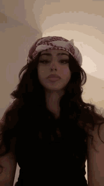 a woman wearing a bandana on her head is standing in a room .