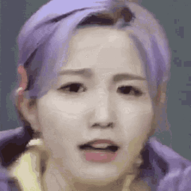 a close up of a woman 's face with purple hair .