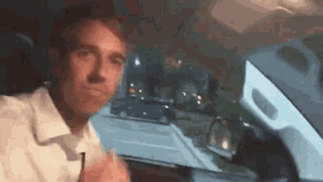 a man is sitting in the driver 's seat of a car at night .