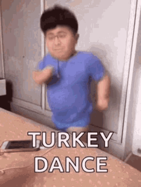 a man in a blue shirt is dancing on a bed with the words `` turkey dance '' written above him .