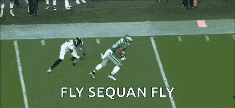 a football player is jumping in the air to catch a ball while another player tries to stop him .