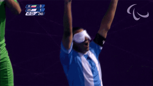 a man wearing a blindfold holds up his hands in the air