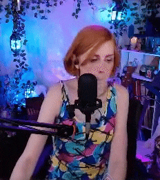 a woman is singing into a microphone while wearing a colorful dress