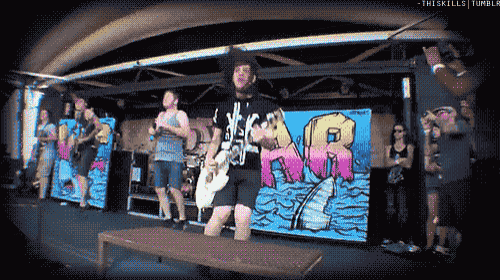 a man playing a guitar in front of a wall that says ' ar '
