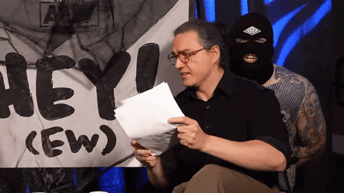 a man holding a piece of paper in front of a sign that says hey new