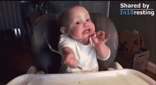 a baby in a high chair with a spoon in his mouth