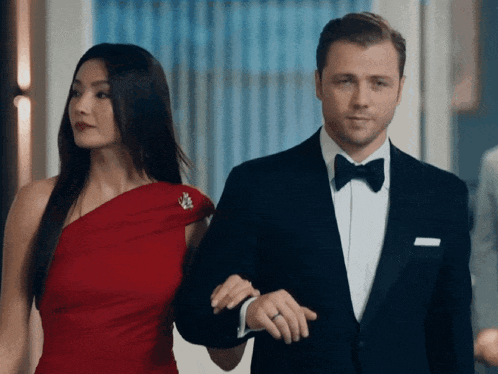 a man in a tuxedo and a woman in a red dress are walking