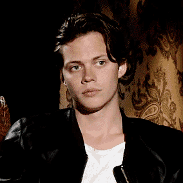 a young man wearing a black jacket and white shirt