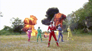 a group of power rangers are standing in a field with an explosion in the background