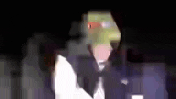 a man in a tuxedo with a mask on his face is standing in the dark .