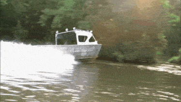 a boat is going down a river with the sun shining through the trees in the background