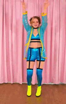 a woman in a blue and yellow outfit is dancing with her arms in the air