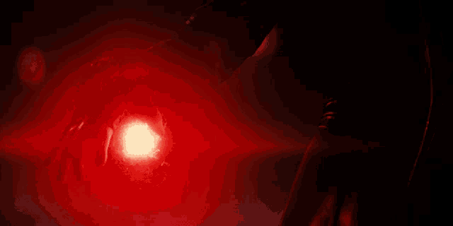 a person 's hand is holding a red light in the dark