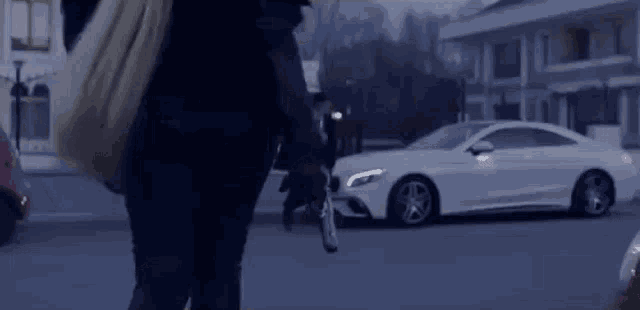 a man is holding a gun in front of a white mercedes benz .