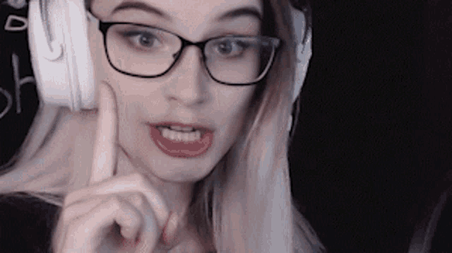 a woman wearing glasses and headphones is making a funny face .