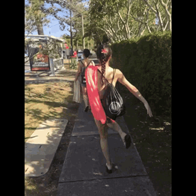 a woman is walking down a sidewalk carrying a bag that says ' abercrombie ' on it