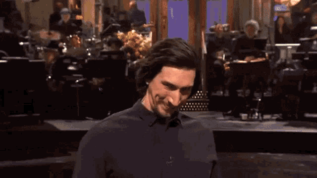 a man with long hair is making a funny face while standing on a stage .