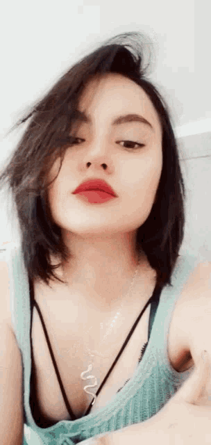 a woman with dark hair and red lipstick is wearing a blue tank top