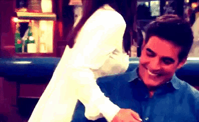a man in a blue shirt is smiling while a woman in a white shirt holds his arm
